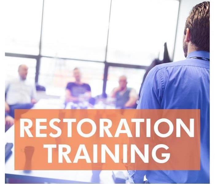 A man with his back turned providing training to staff.